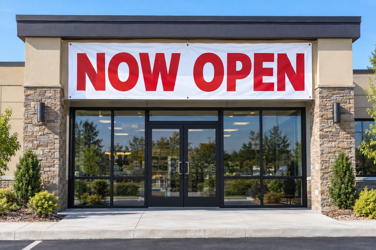 A Now Open vinyl banner on a single story commercial building.