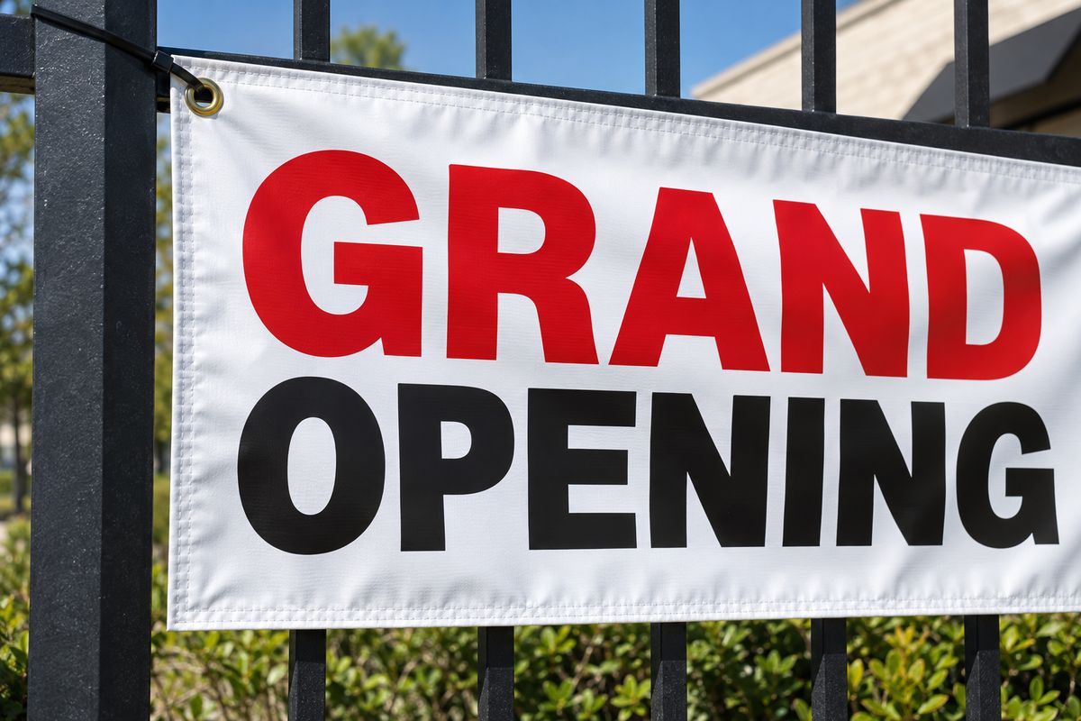 A close up of a Grand Opening banner corner with a brass grommet and zip tie.