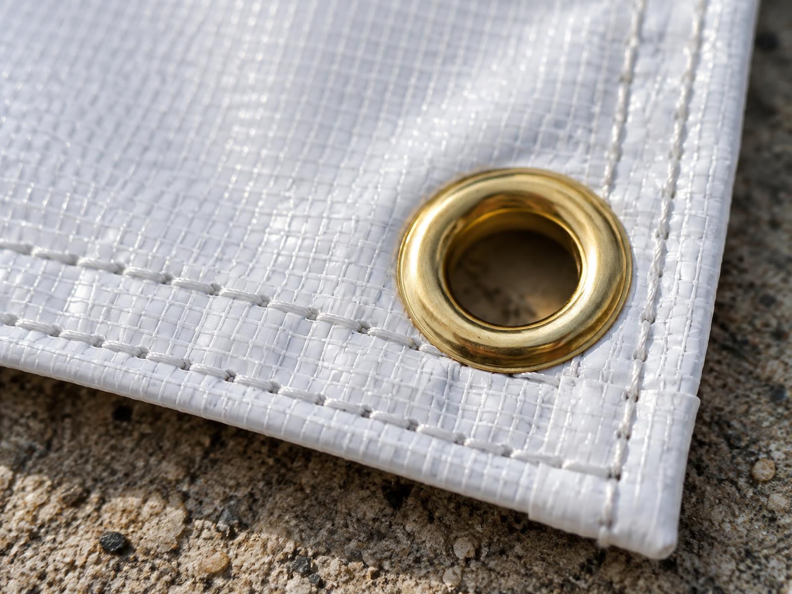 Close up of a banner corner showing the sewn double hem and a brass grommet